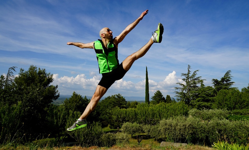 Daniel pikes his legs in front of him making a parallel line with the ground. He supports himself by a metal railing.